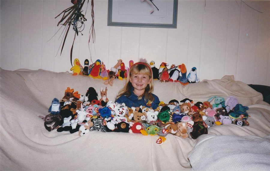 Hannah as a kid, grinning behind her entire Beanie Baby collection